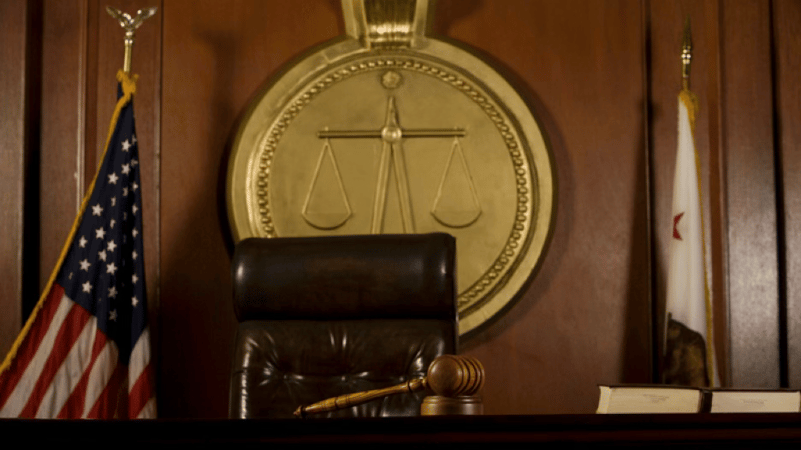 Photo of a judges chair in a courtroom with a gavel on the desk